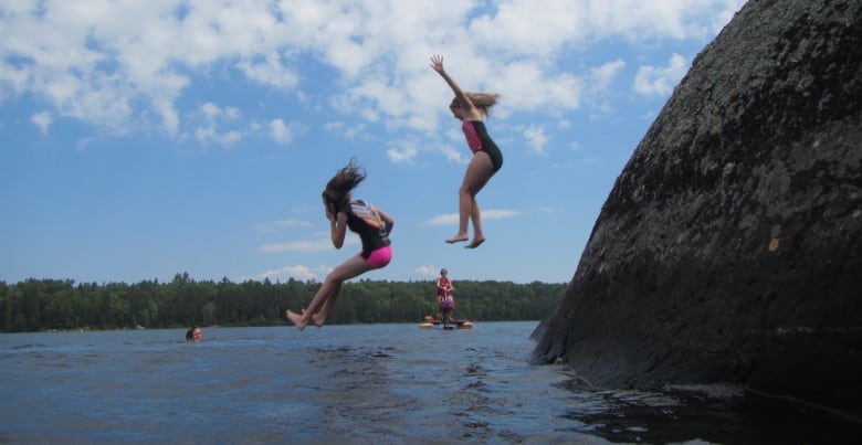 Two people jumping into a lake.