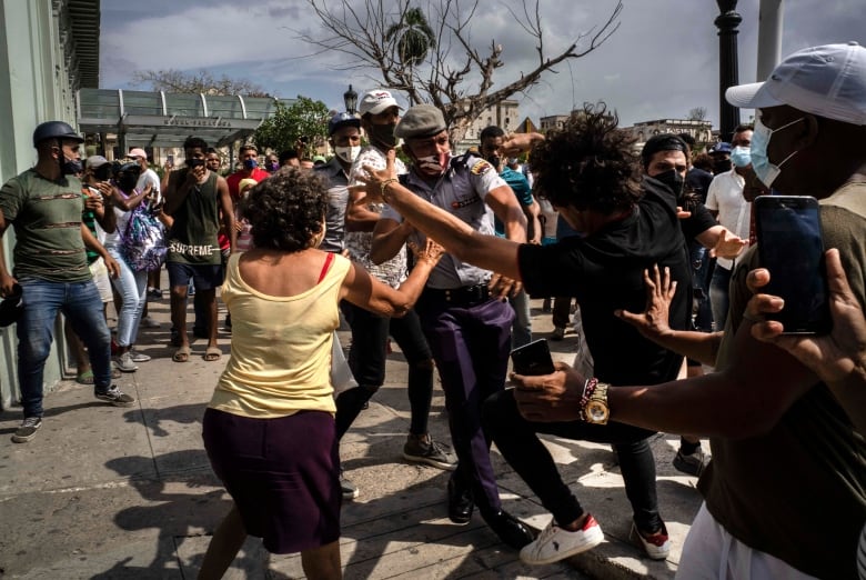 Police scuffle and detain an anti-government demonstrator during a protest in Havana, Cuba, Sunday July 11, 2021. Hundreds of demonstrators went out to the streets in several cities in Cuba to protest against ongoing food shortages and high prices of foodstuffs, amid the new coronavirus crisis.