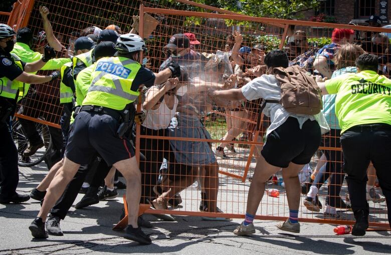 Several police officers and security staff struggle with civilians.