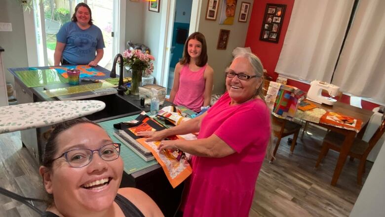 Four people working on quilts.