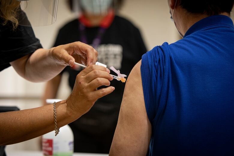 A person gets a COVID-19 vaccination in their shoulder.