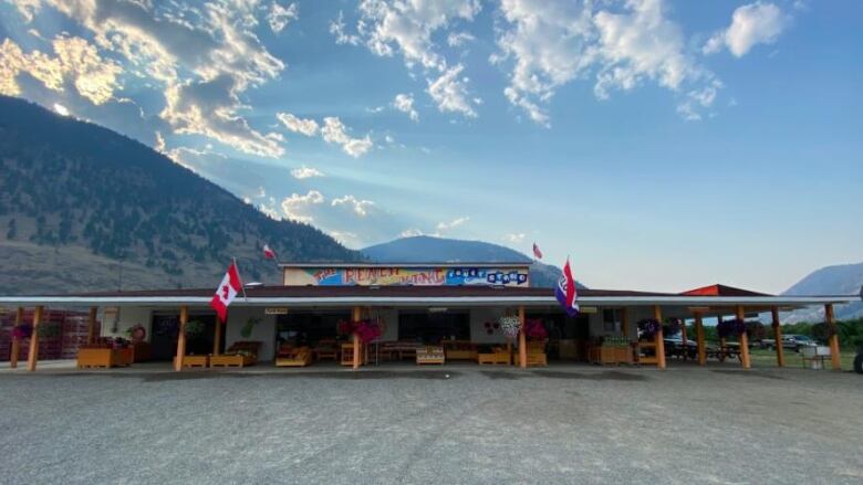 A fruit stand reading 'The Peach King Fruit Stand', with mountains behind it.