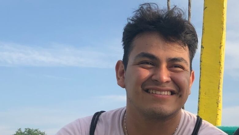 A young man in a t-shirt smiles for a photo