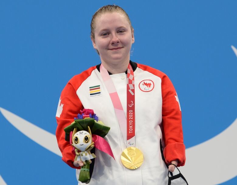 A grinning woman with a red and white jacket on and a gold medal around her neck