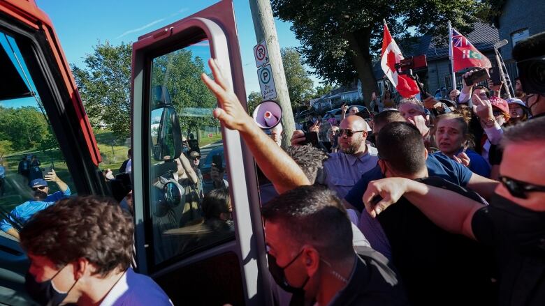 Mounties surround Justin Trudeau as he boards a campaign bus.