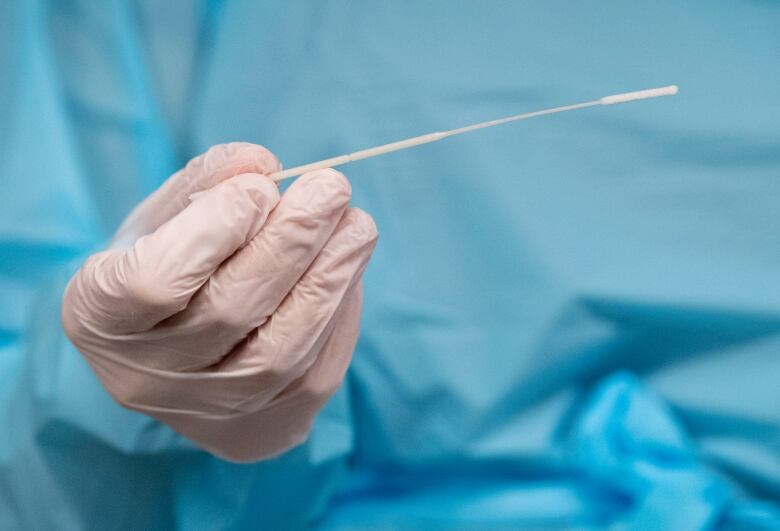 A nurse holds a swab before testing a patient.