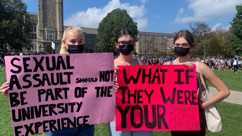 Students at a protest hold signs and wear masks. 