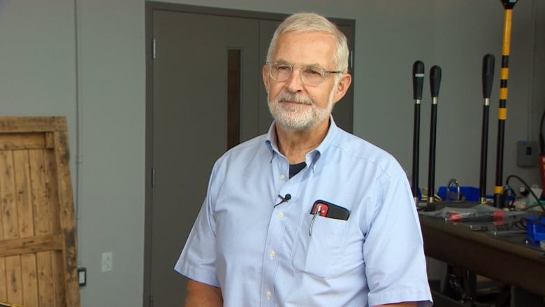 A man wearing a short sleeve blue shirt with a beard looks at the camera.