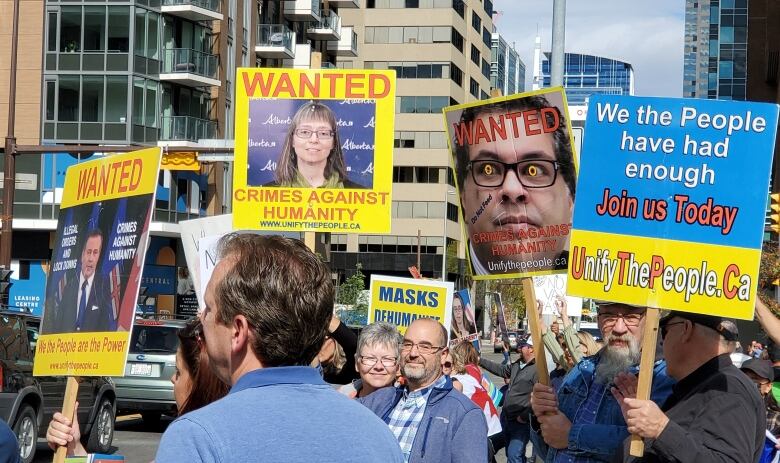 A protest crowd in which people are carrying large signs.