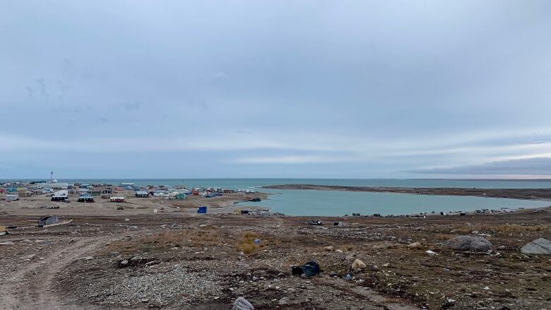 A scattering of houses and buildings on the shores of an expanse of ocean.