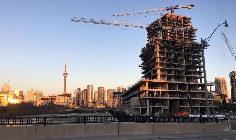 A condo building under construction, with a view of downtown Toronto in the background.