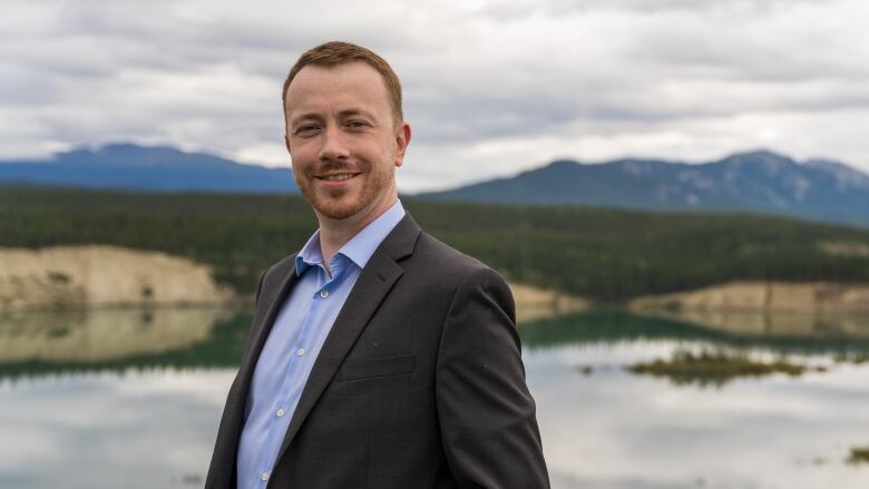 A man standing on a hill overlooking a lake