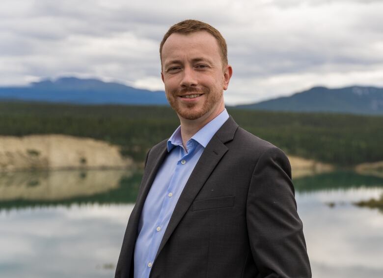 A man standing on a hill overlooking a lake