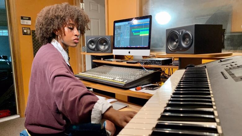 A Black woman with brown hair at a piano