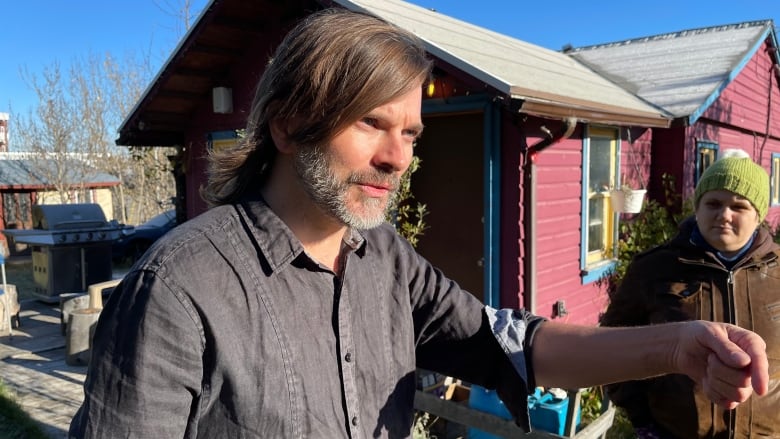 Man stands in front of purple house in downtown Whitehorse.