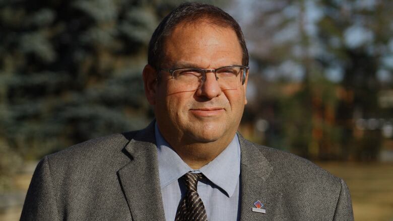 A man with glasses and a grey suit. 