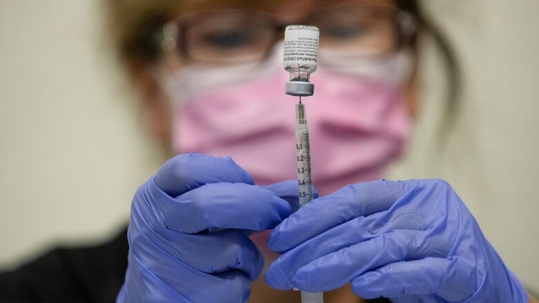 A nurse fills up a syringe with a COVID-19 vaccine. 