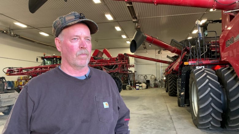 A man stands in front of a tractor.