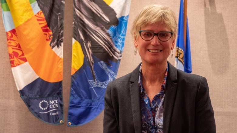 A smiling white woman in city council chambers.