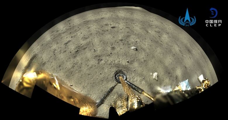 Legs of the Chang'e 5 spacecraft are on the lunar surface. In the background are several rocks.