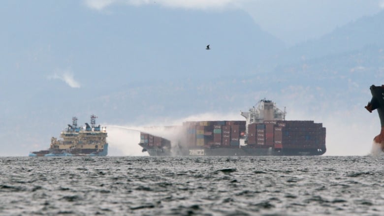 Ships work to control a fire onboard the MV Zim Kingston about eight kilometres from the shore in Victoria on Oct. 24, 2021. The container ship caught fire on Saturday and 16 crew members were evacuated and brought to Ogden Point Pier. 