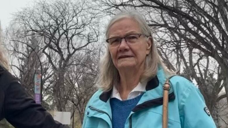 An elderly woman in a blue jacket.