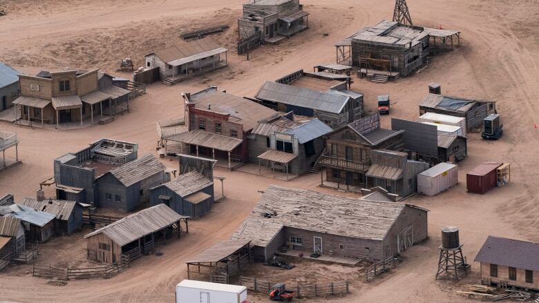 An aerial view of a Western movie set with several wooden buildings in the desert. 