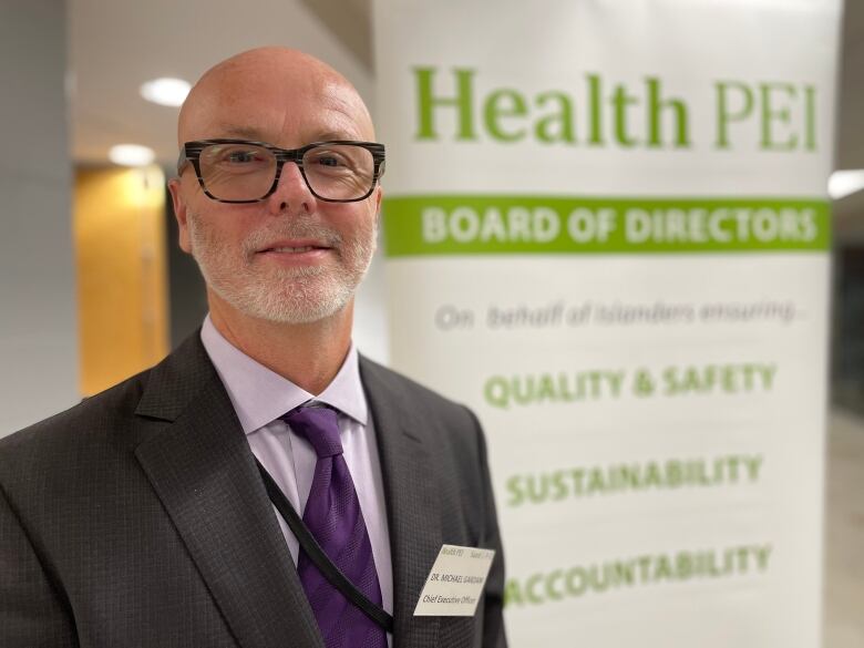 Bearded man with glasses in front of Health P.E.I. sign. 