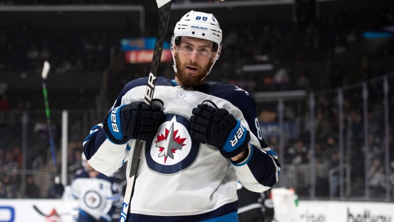 A male hockey player is seen looking at the camera while celebrating a goal with both his hands in his chest.