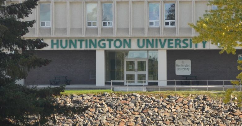 Words on a building reads 'Huntington University' framed through trees