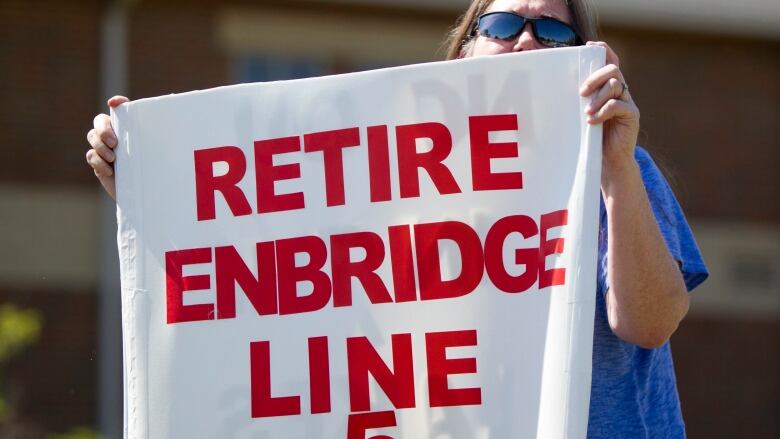 A woman holds a protest sign that says 