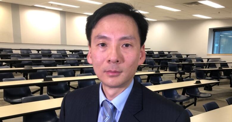 A man in a suit in a university classroom.