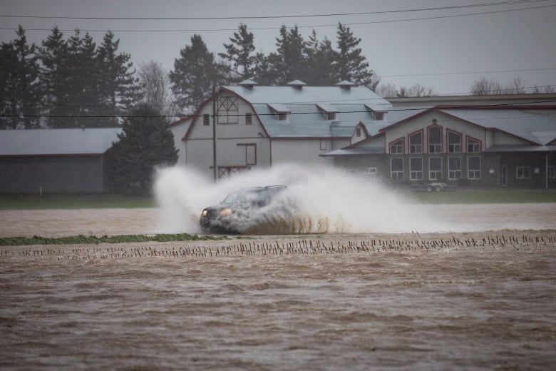 A car drives through a flooded road during flooding in Abbotsford, British Columbia on Monday, November 15, 2021. 