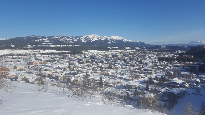 Overlooking a small city in winter, with mountains in the background.