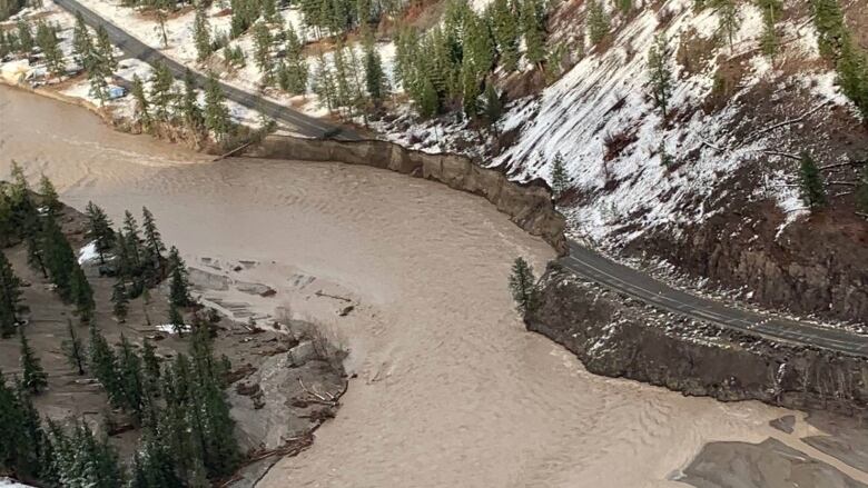 An aerial shot of muddy brown water encroaching on a roadway.