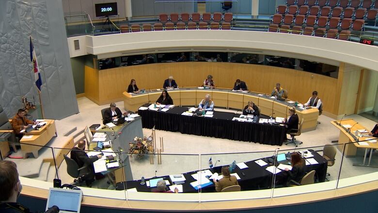 Looking down on a government assembly, with people at a circle of tables in a large room.