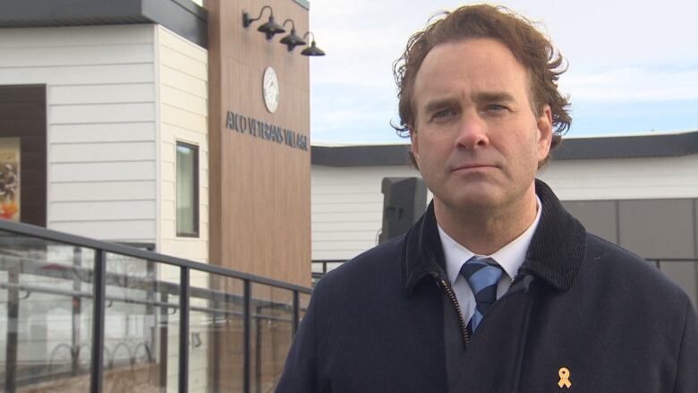 A man in a tie with long brown hair is beings interviewed for camera