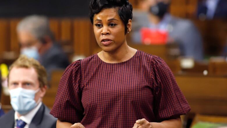 A woman in a red spotted blouse rises in the House of Commons.