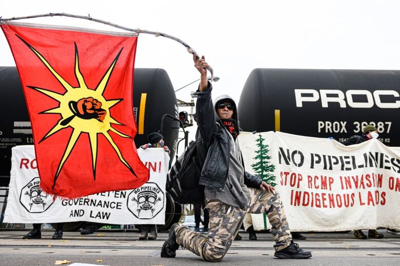 Man holds flacg infront of blockade in support of Wet'suwet'en land defenders in Toronto. 