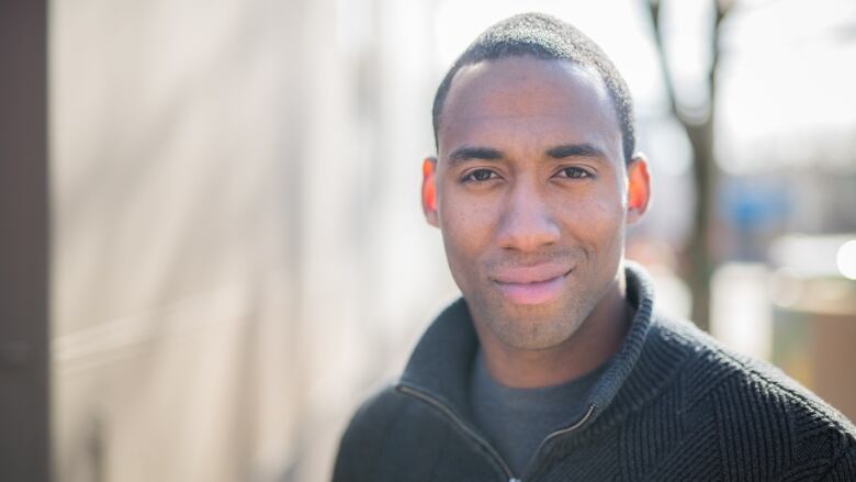 A Black man wearing a patterned sweater