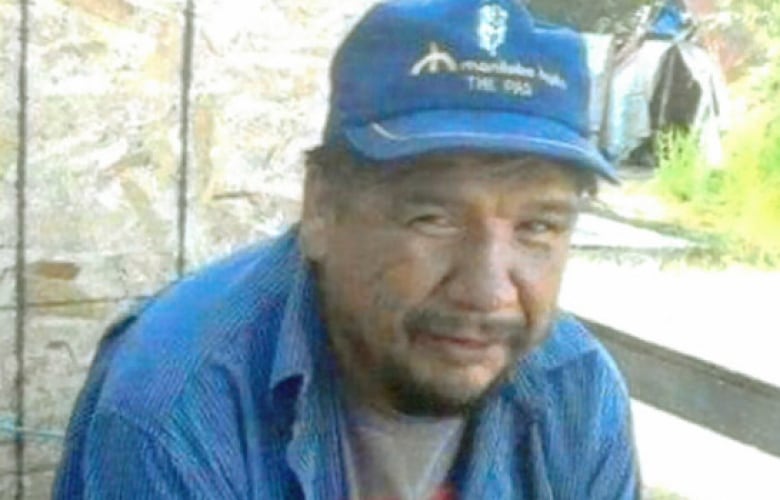 A portrait of a man in a ball cap and a blue button-up shirt.