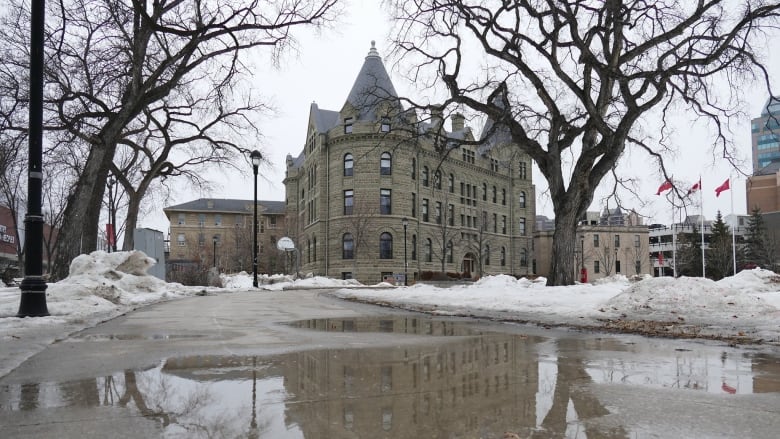 A puddle forms next to snow banks on a university campus.