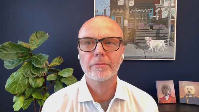 Man in white shirt sits against a home background during a virtual interview. 