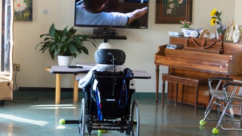 A resident in a wheelchair watches television in a seniors' home.