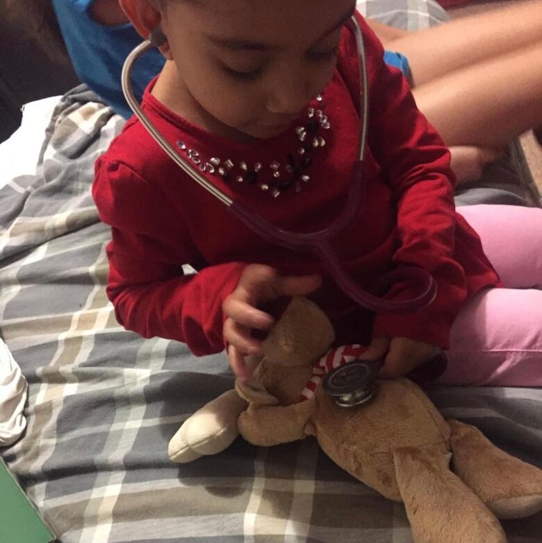 A young Black girl using a stethoscope