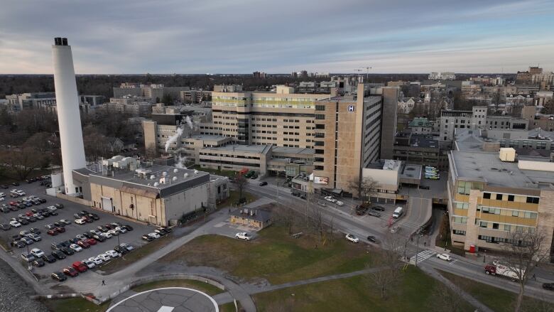 An aerial shot of a large, concrete building with a huge, white smoke stack and large parking lot. It's a sunny, clear day.