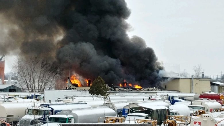 Smoke billows into the air following an explosion in an industrial area in winter.