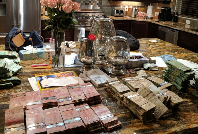 A kitchen countertop is shown with stacks of $50 bills.