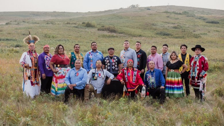 Northern Cree members stand in an open field. 