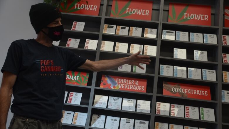 A man, Jamy McKenzie, displays cannabis products on the shelf of a store in Sudbury.